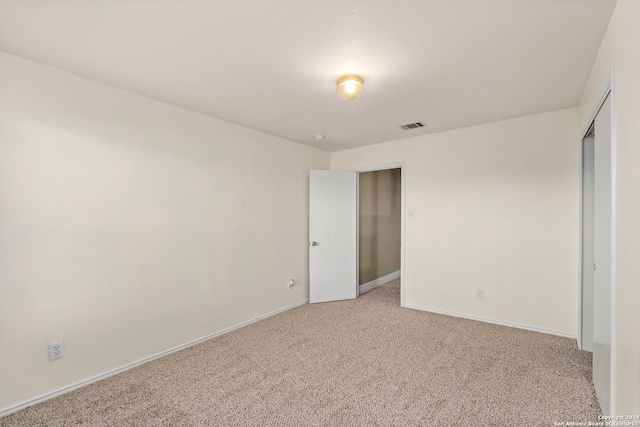 unfurnished bedroom with light carpet and a closet