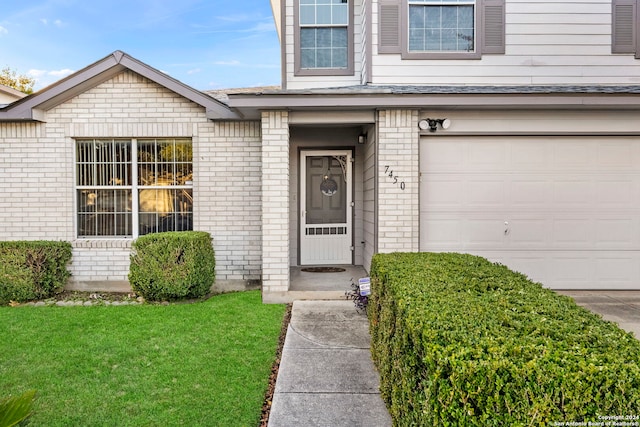 view of exterior entry featuring a lawn and a garage