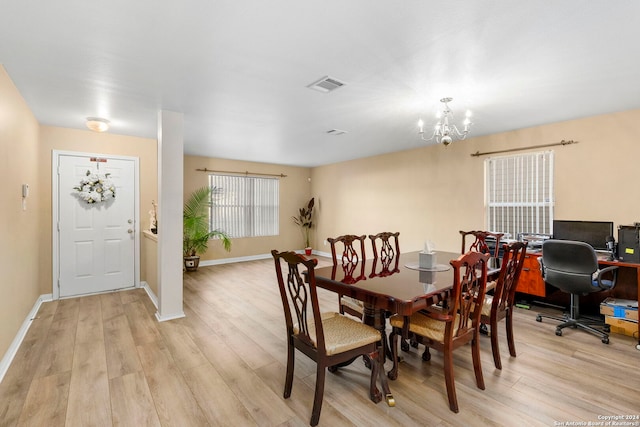 dining room with light hardwood / wood-style flooring and an inviting chandelier