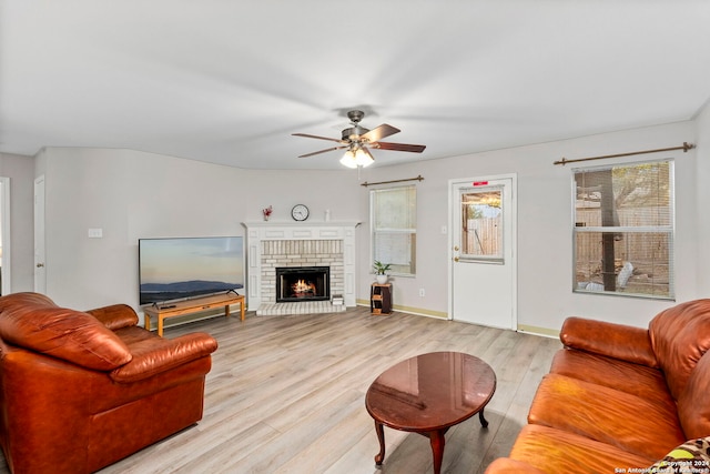 living room featuring ceiling fan, light hardwood / wood-style floors, and a brick fireplace