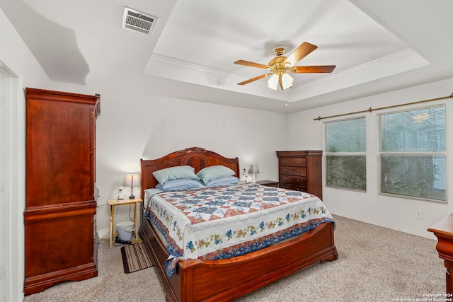 carpeted bedroom with a raised ceiling, ceiling fan, and ornamental molding