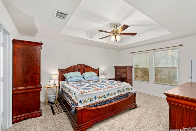 bedroom with ceiling fan, light colored carpet, and a tray ceiling