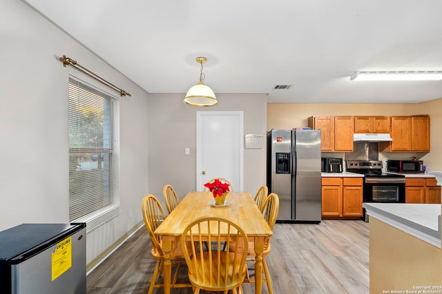 kitchen with light hardwood / wood-style floors, decorative light fixtures, and appliances with stainless steel finishes