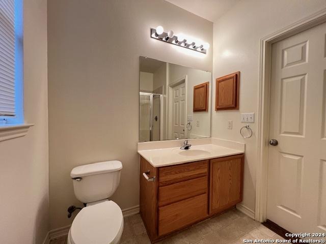 bathroom featuring tile patterned floors, vanity, toilet, and a shower with shower door