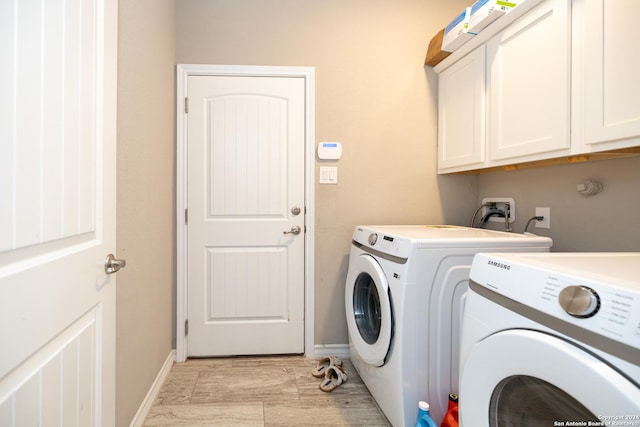 clothes washing area with washing machine and clothes dryer, cabinets, and light hardwood / wood-style floors