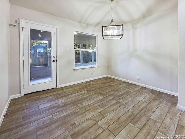 unfurnished dining area with hardwood / wood-style floors and a notable chandelier