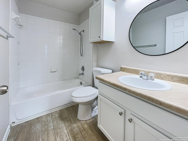 full bathroom with hardwood / wood-style floors, vanity, tiled shower / bath combo, and toilet