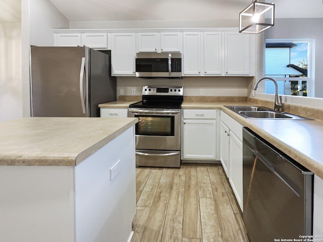 kitchen featuring white cabinets, stainless steel appliances, hanging light fixtures, and sink