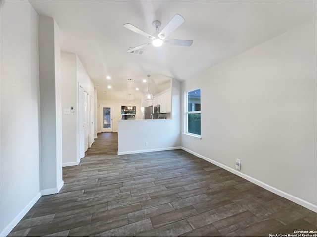 unfurnished living room featuring ceiling fan and dark wood-type flooring