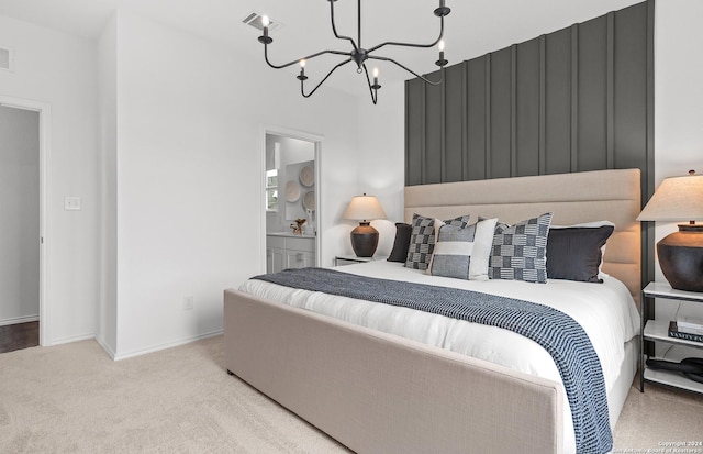 bedroom with a chandelier, light colored carpet, and ensuite bath