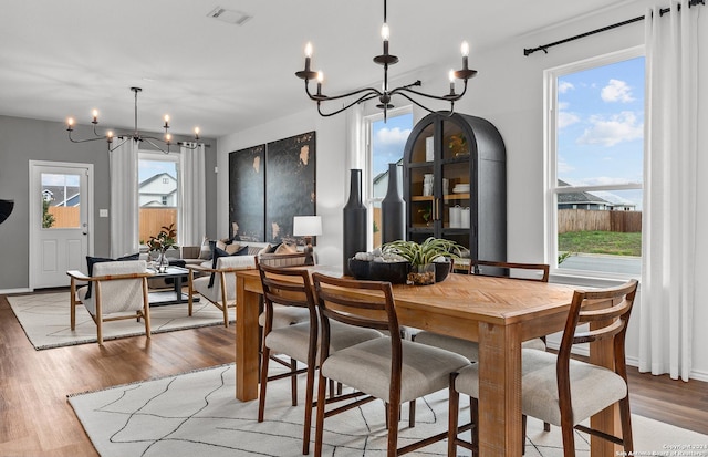 dining room with hardwood / wood-style floors, plenty of natural light, and an inviting chandelier