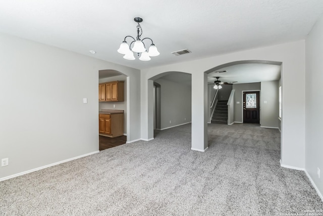 carpeted empty room featuring ceiling fan with notable chandelier