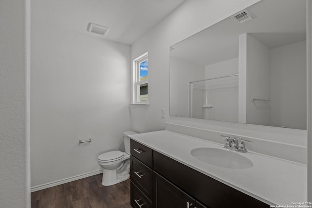 bathroom with vanity, toilet, wood-type flooring, and a shower