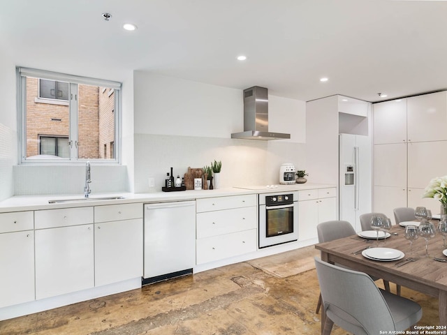 kitchen with white appliances, white cabinetry, wall chimney exhaust hood, and sink