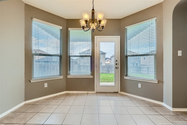 doorway with light tile patterned flooring, a healthy amount of sunlight, and an inviting chandelier