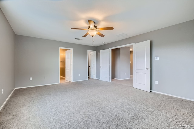 unfurnished bedroom featuring ceiling fan, a closet, a spacious closet, and light carpet