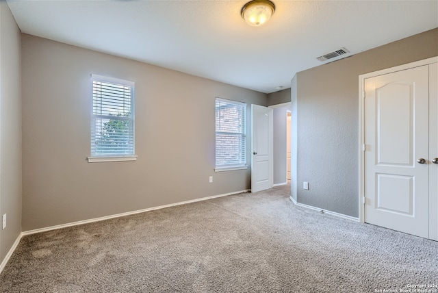 unfurnished bedroom featuring carpet, a closet, and multiple windows