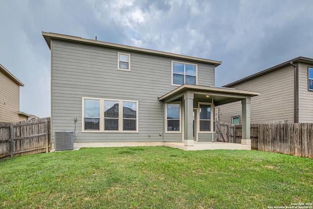 rear view of property with a yard, a patio, and central air condition unit