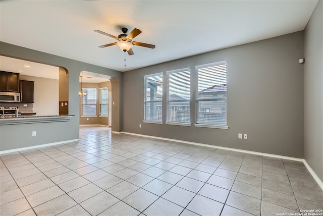 unfurnished living room featuring ceiling fan with notable chandelier and light tile patterned flooring