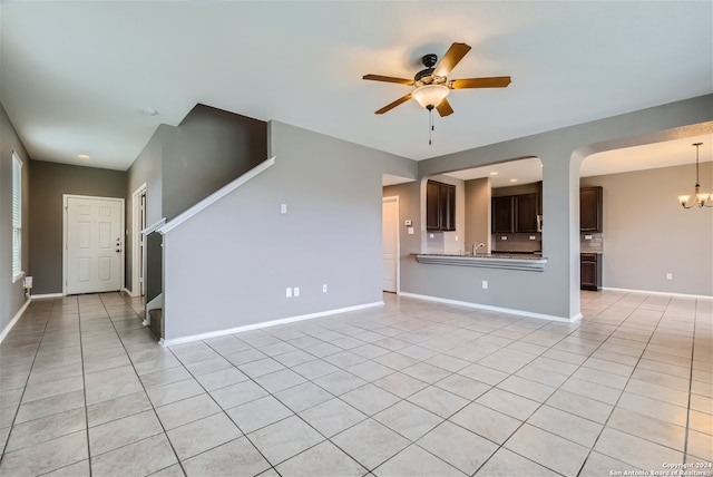 unfurnished living room with ceiling fan with notable chandelier, light tile patterned floors, and sink