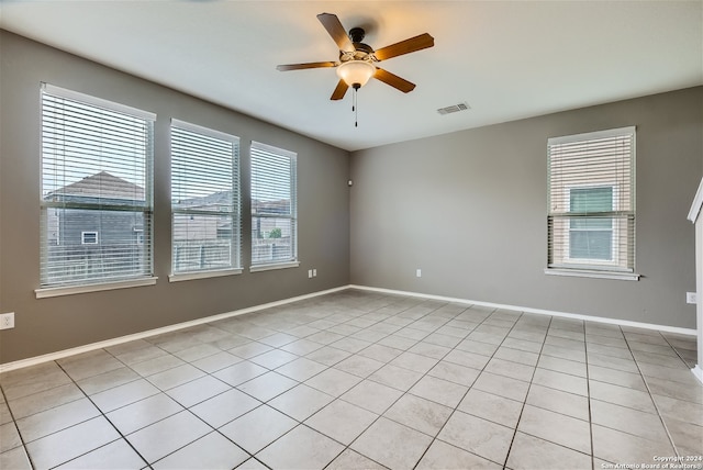 spare room with ceiling fan, a healthy amount of sunlight, and light tile patterned flooring