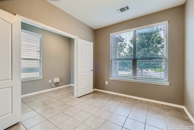 unfurnished bedroom with multiple windows and light tile patterned floors