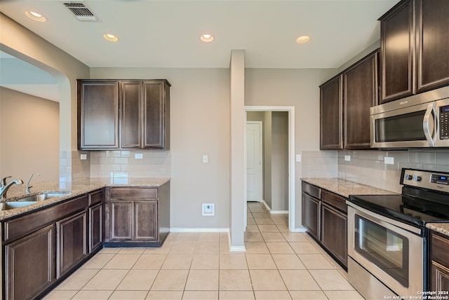 kitchen with decorative backsplash, light stone countertops, sink, and stainless steel appliances