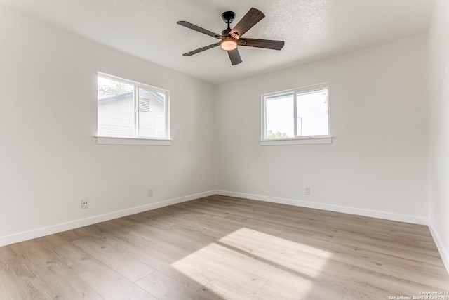 unfurnished room with ceiling fan, a textured ceiling, a wealth of natural light, and light hardwood / wood-style flooring