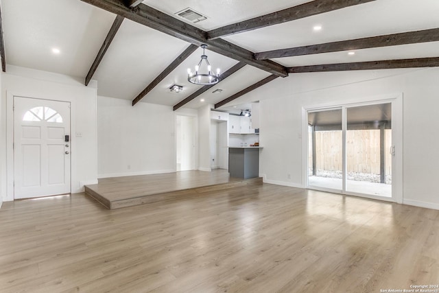 unfurnished living room with lofted ceiling with beams, light hardwood / wood-style floors, a wealth of natural light, and a notable chandelier