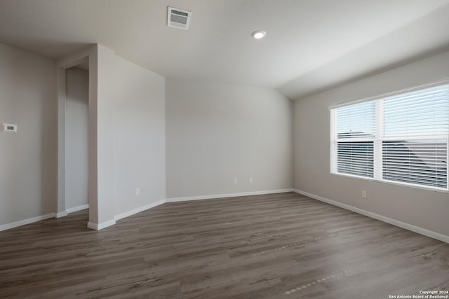 empty room featuring dark wood-type flooring and lofted ceiling