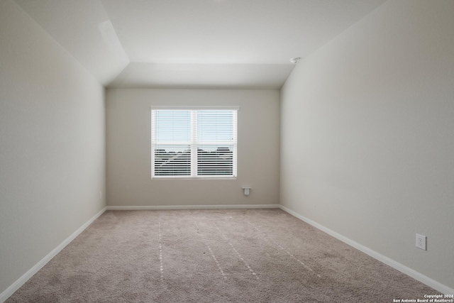 spare room with carpet flooring and lofted ceiling