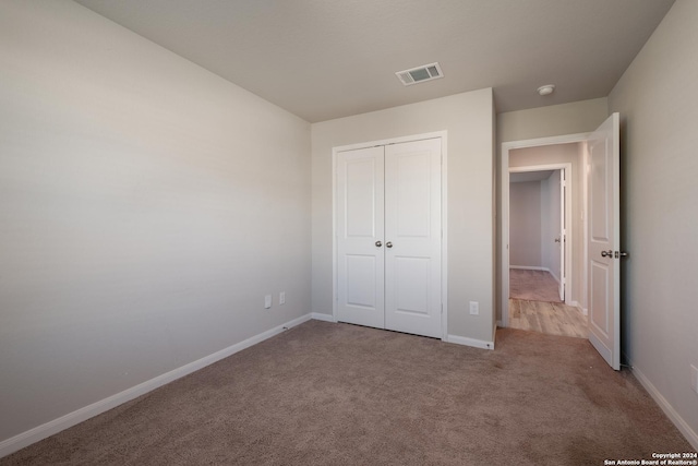 unfurnished bedroom featuring light carpet and a closet