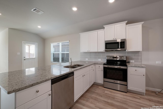 kitchen featuring white cabinetry, stainless steel appliances, lofted ceiling, and light hardwood / wood-style floors