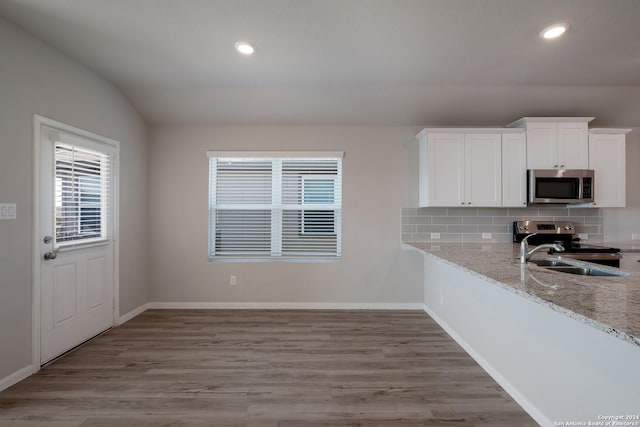 kitchen featuring light stone countertops, white cabinetry, stainless steel appliances, tasteful backsplash, and light wood-type flooring