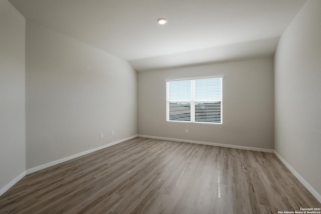 spare room featuring lofted ceiling and wood-type flooring