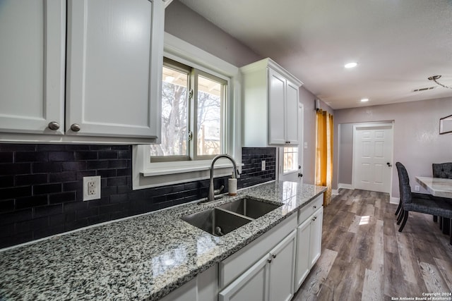 kitchen featuring light stone countertops, white cabinetry, sink, backsplash, and light hardwood / wood-style floors