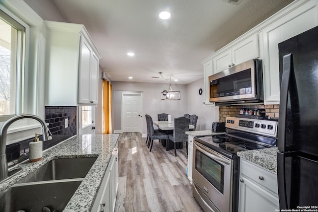 kitchen with pendant lighting, sink, light hardwood / wood-style flooring, appliances with stainless steel finishes, and white cabinetry