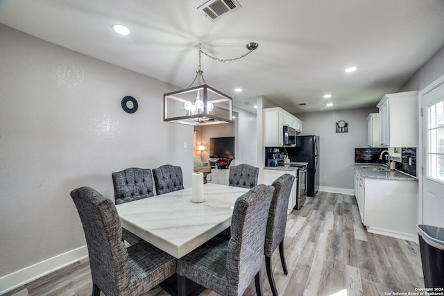 dining room featuring light hardwood / wood-style floors, a notable chandelier, and sink