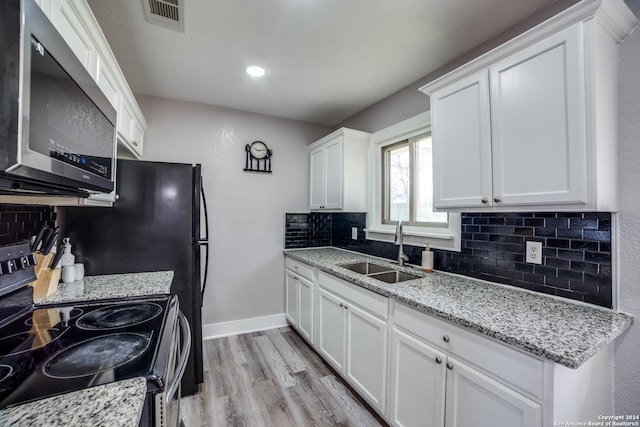 kitchen with light stone countertops, appliances with stainless steel finishes, light wood-type flooring, sink, and white cabinets