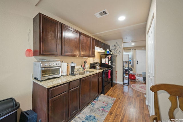 kitchen with dark hardwood / wood-style flooring, light stone counters, dark brown cabinetry, sink, and electric range