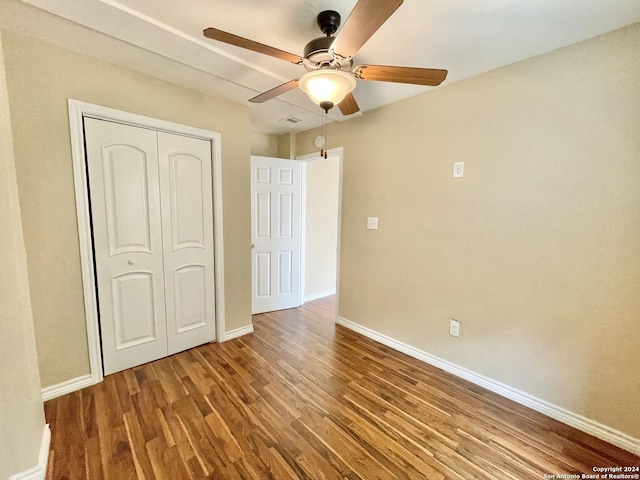 unfurnished bedroom with ceiling fan, wood-type flooring, and a closet