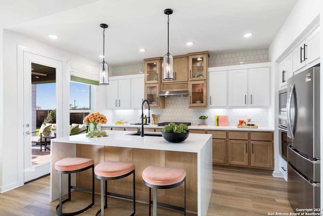 kitchen with white cabinetry, a kitchen island with sink, sink, and stainless steel appliances