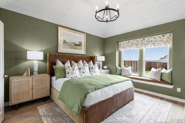 bedroom featuring hardwood / wood-style floors, wood ceiling, and an inviting chandelier