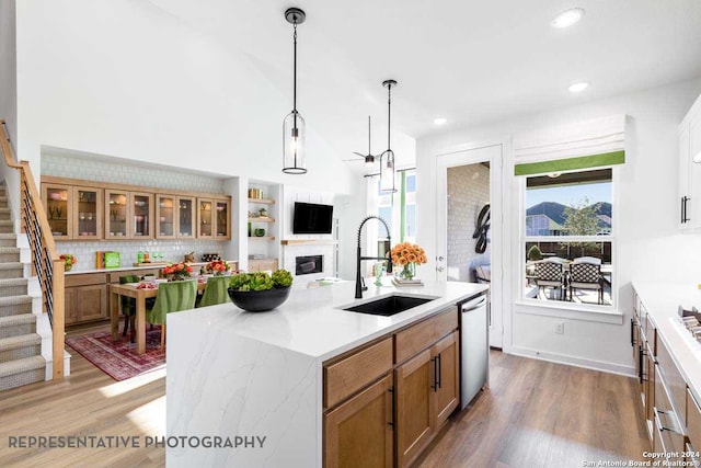 kitchen with dishwasher, sink, an island with sink, pendant lighting, and wood-type flooring