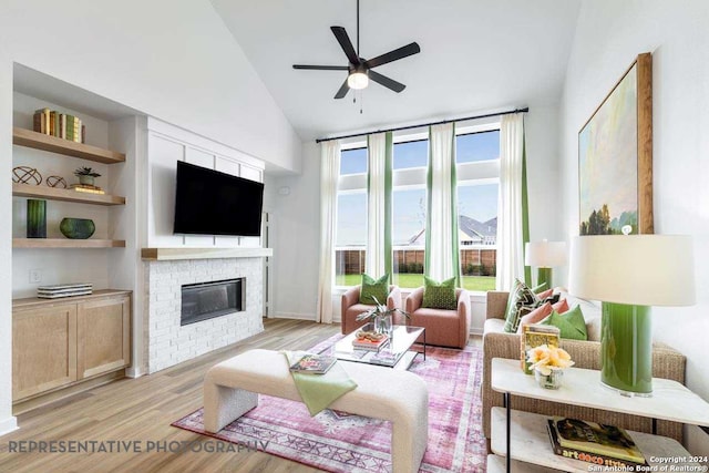 living room featuring light wood-type flooring, ceiling fan, high vaulted ceiling, built in features, and a fireplace