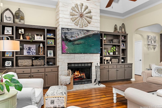 living room featuring ceiling fan, a fireplace, ornamental molding, and hardwood / wood-style flooring