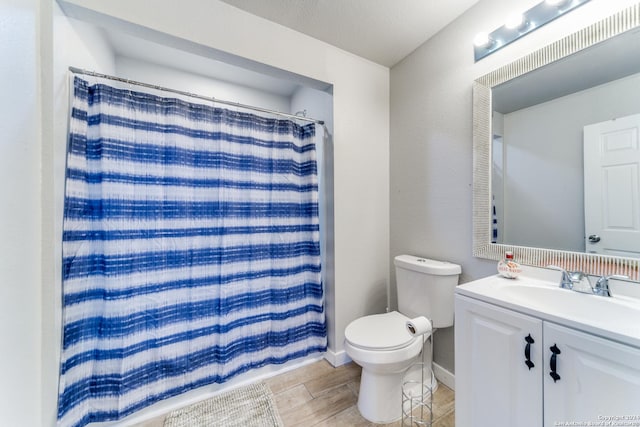 bathroom with walk in shower, vanity, a textured ceiling, hardwood / wood-style floors, and toilet