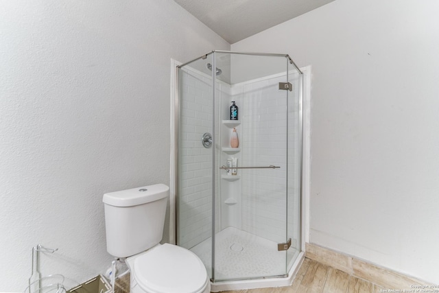 bathroom featuring hardwood / wood-style floors, a textured ceiling, toilet, and a shower with door