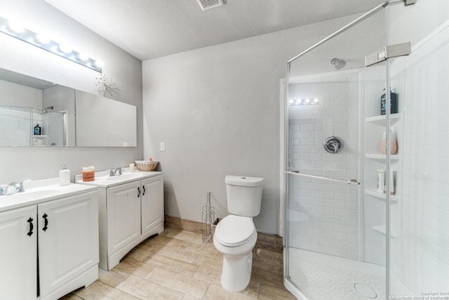 bathroom with a textured ceiling, vanity, toilet, and walk in shower