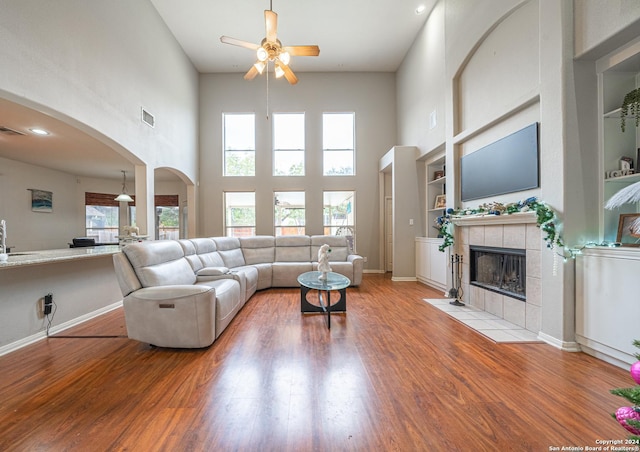 living room with built in shelves, light hardwood / wood-style floors, a towering ceiling, and a wealth of natural light